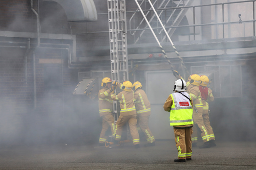 Firefighters carrying out a ladder drill at their pass out ceremony on 2nd December 2022, with the Incident Commander overseeing the exercise.